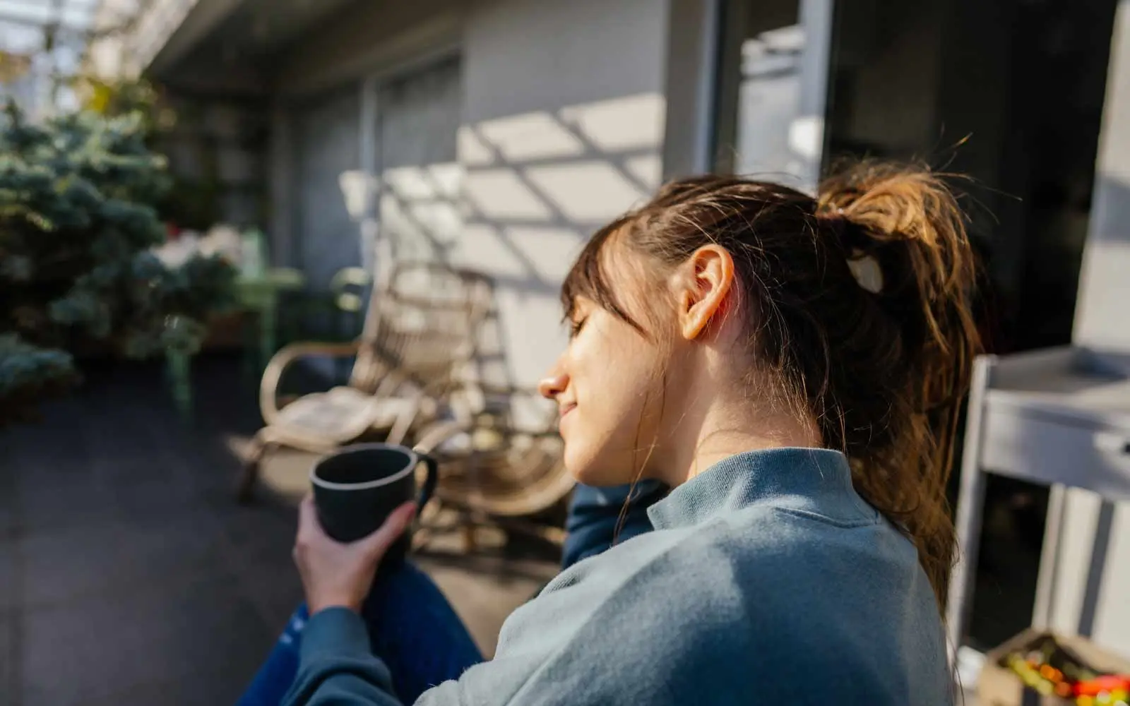 En kvinne nyter en kopp kaffe i solveggen