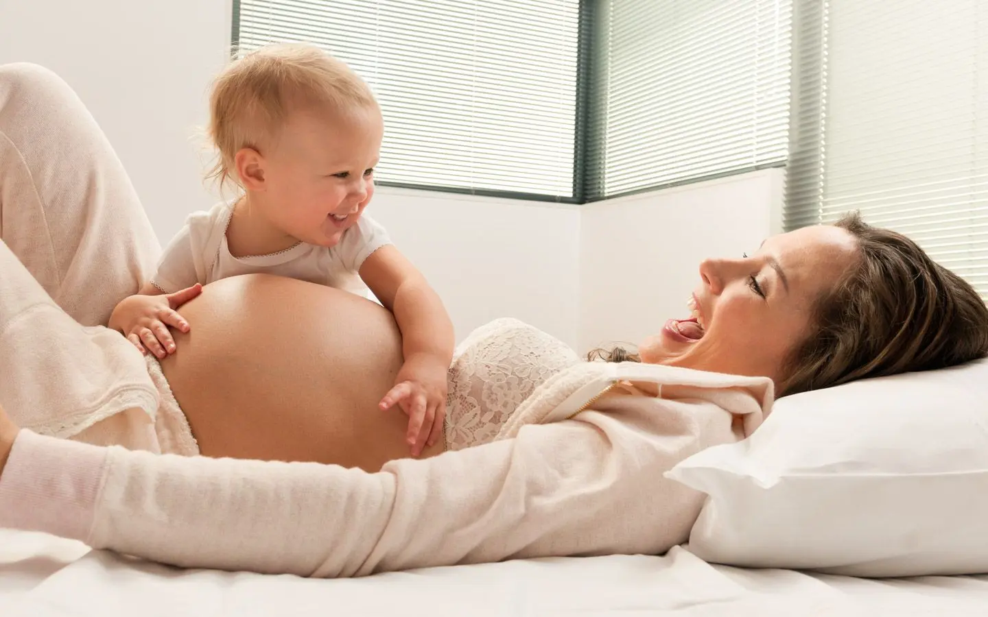 Gravid kvinne med en lite barn som ler i sofaen