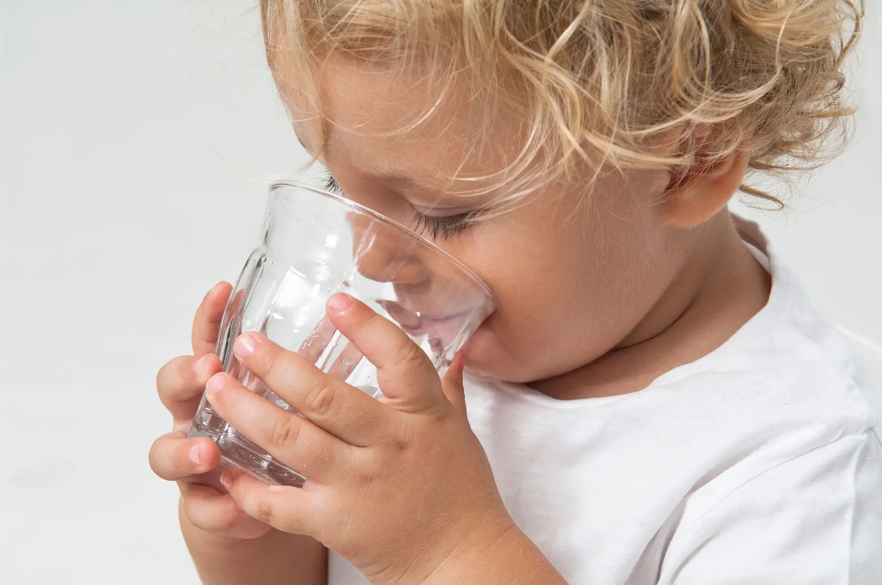 En liten gutt drikker av et glass