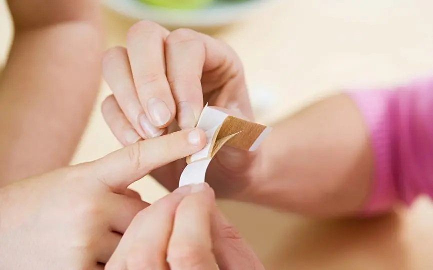 Barn som får plaster på finger av en voksen