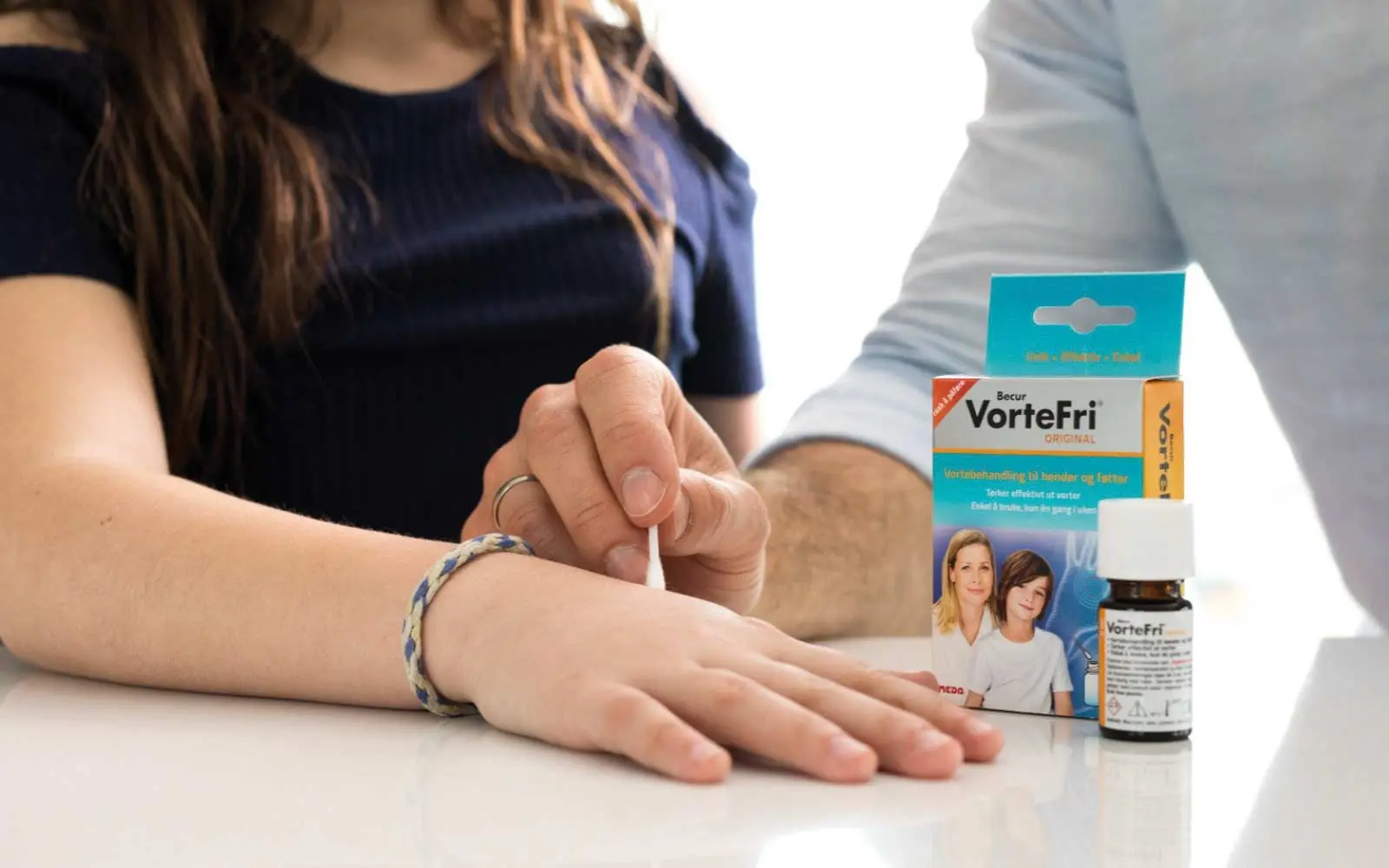 Hånden til en lege som tar en q-tips med middel på hånden til en jente