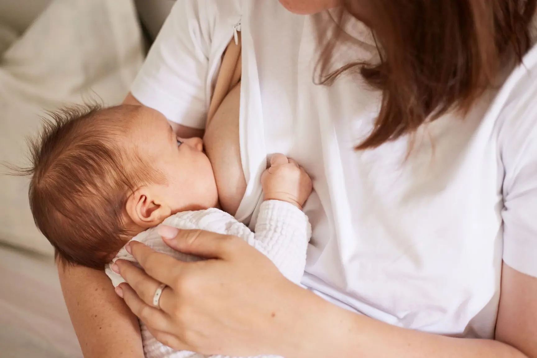 En kvinne i hvite t-skjorte ammer en baby