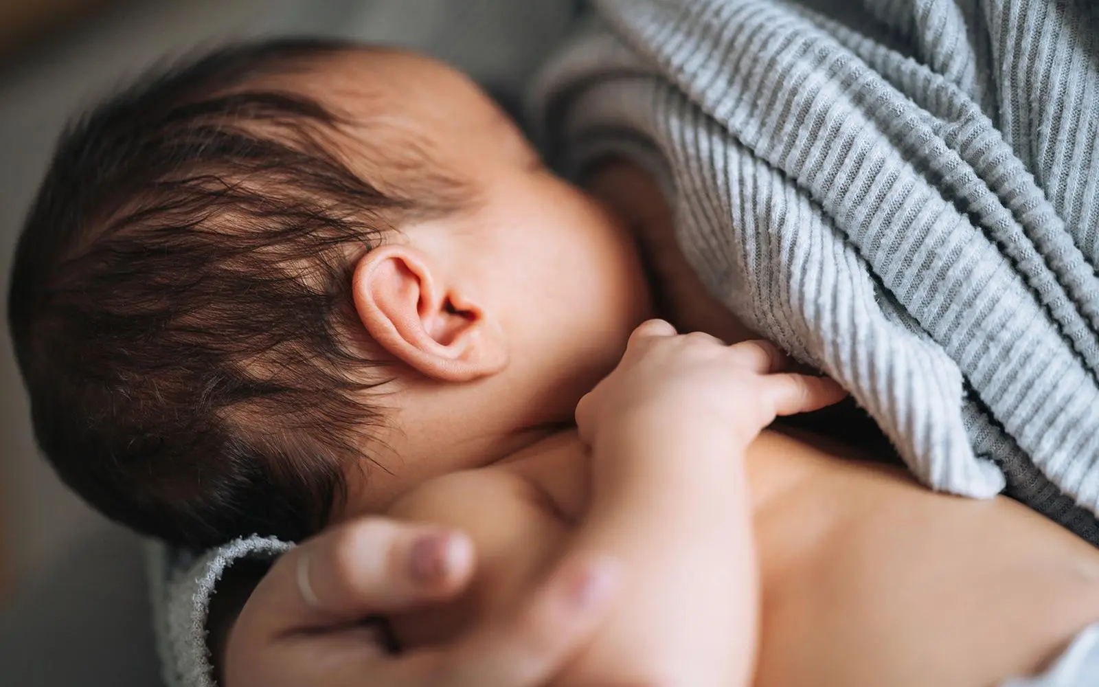 Bilde av baby som ammer av mors bryst.