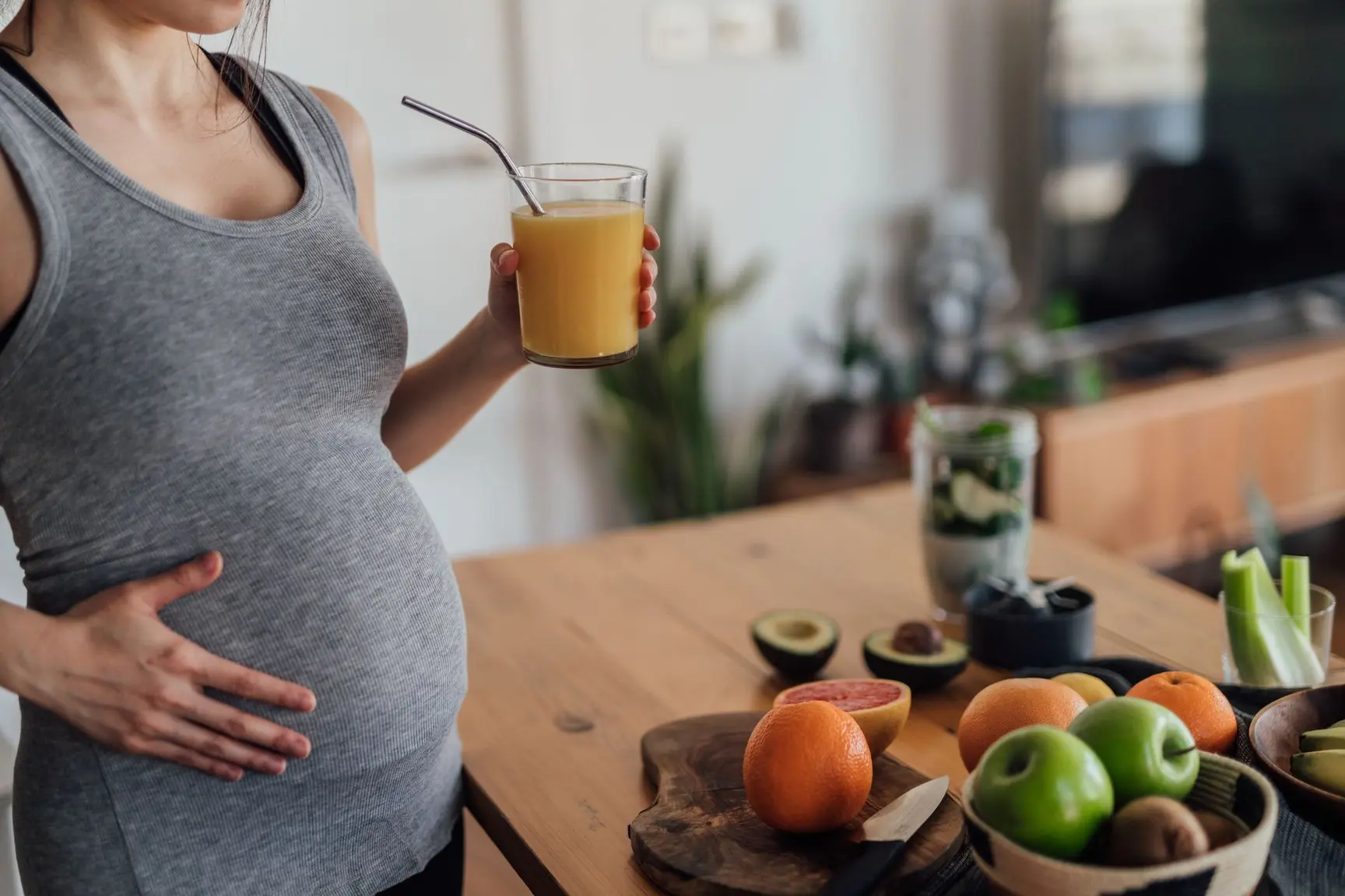 Gravid kvinne holder en hånd på magen