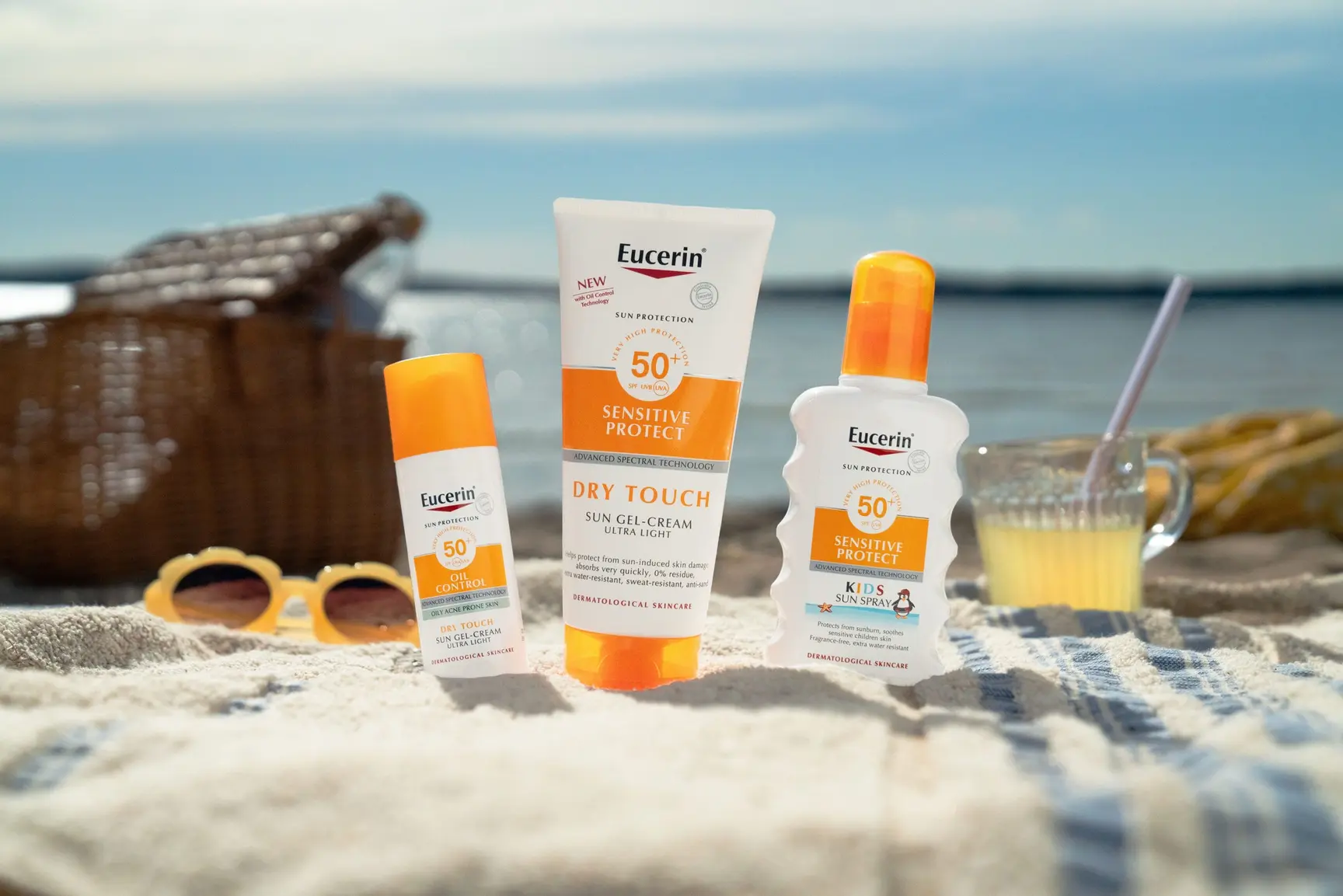 Bilde av solbriller og Eucerin solkrem på en strand