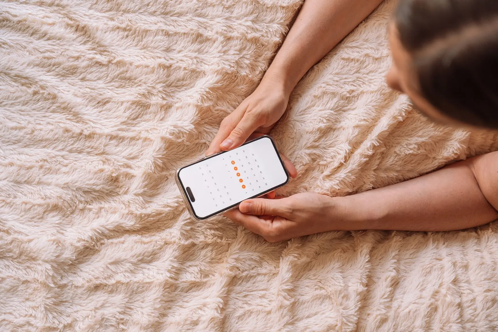 En kvinne holder en telefon i hånden med en kalender