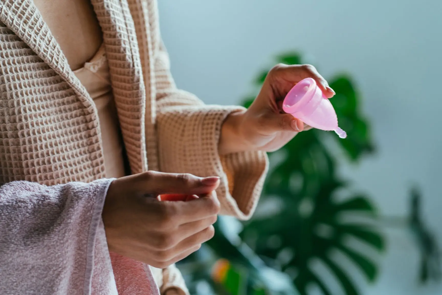 En kvinne holder en rosa menskopp