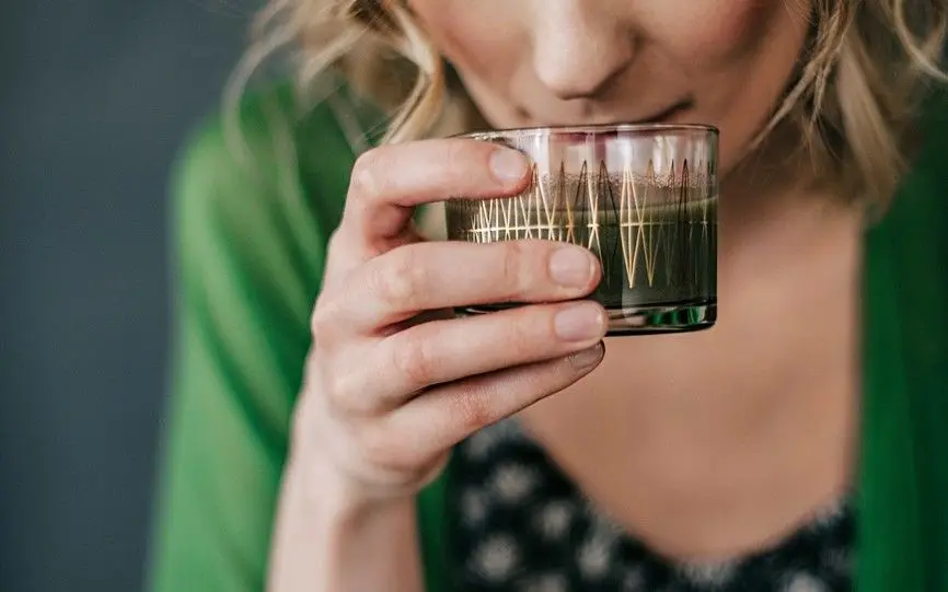 En kvinne holder et glass opp til munnen