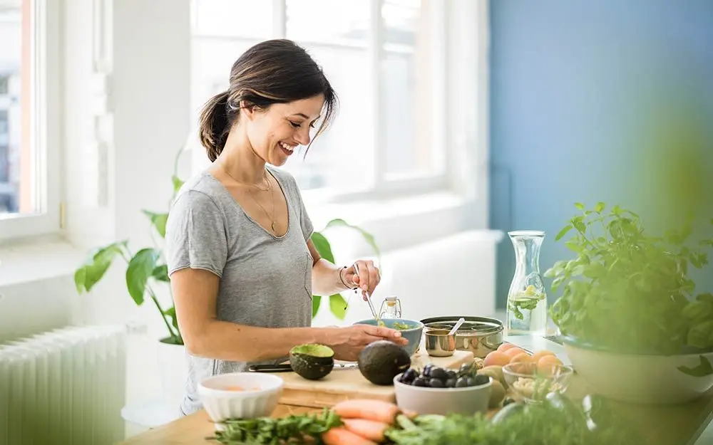 En kvinne står på et kjøkken og lager salat