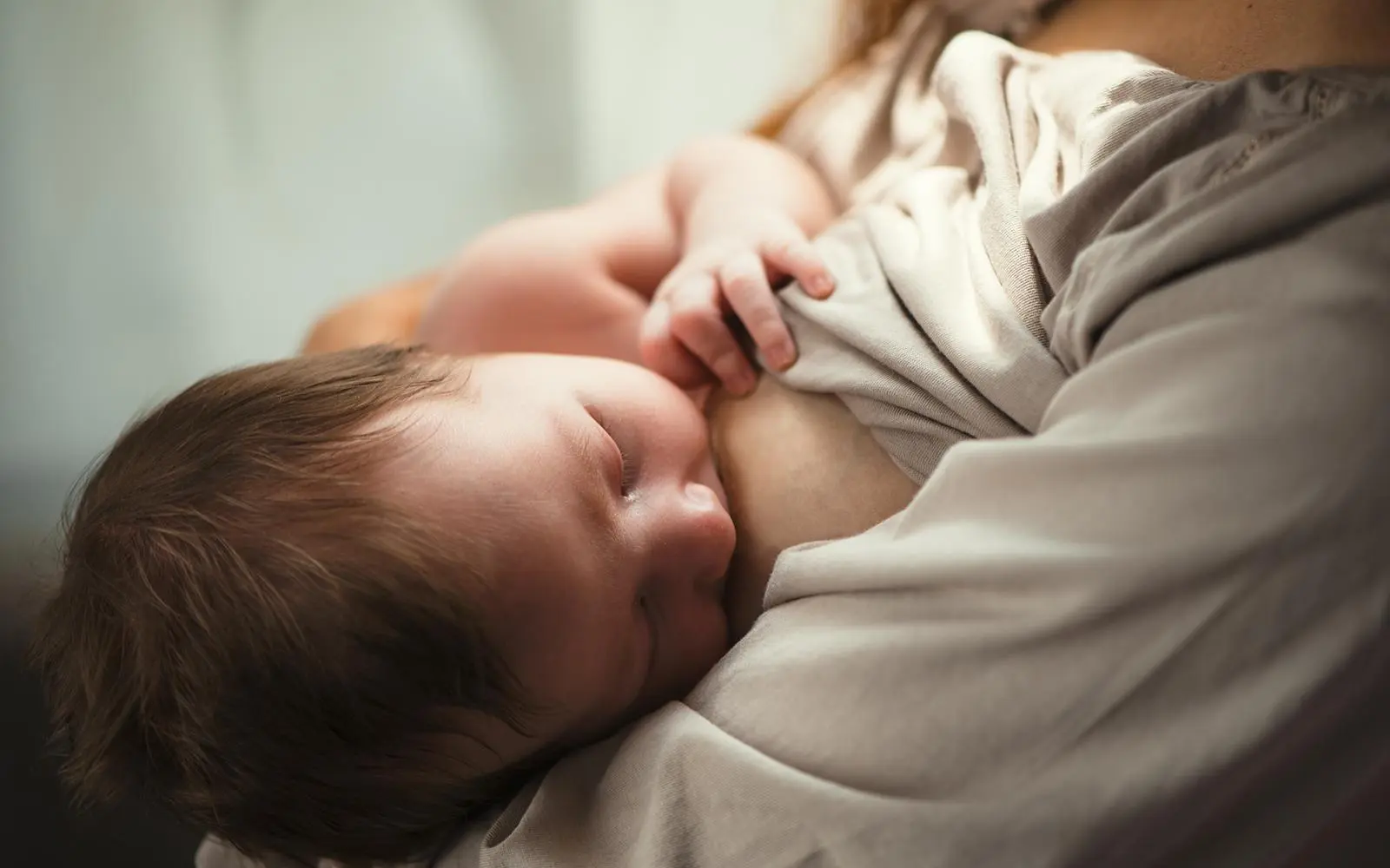 Bilde av baby som sover ved brystet.