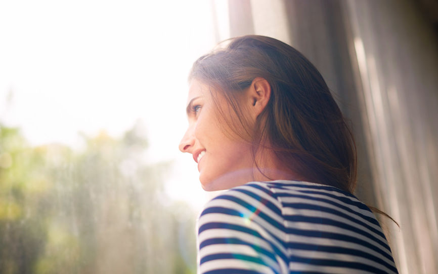 Bilde av en kvinne som smiler og ser ut av vinduet.