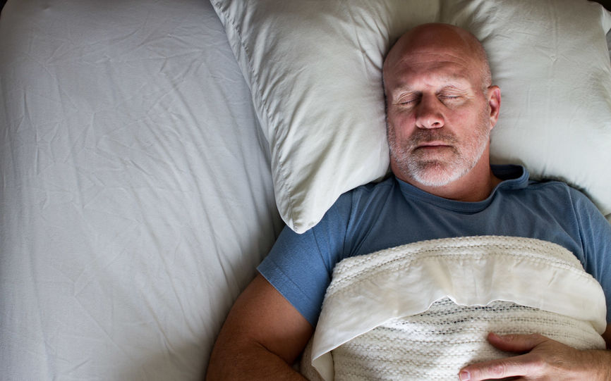 Bilde av en eldre mann som ligger i sengen og sover.