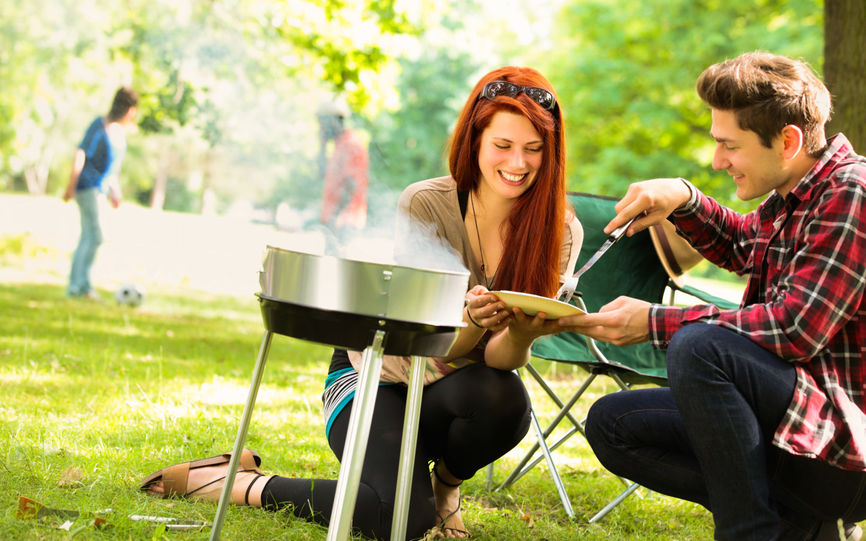 bilde av enkvinne og en mann i en park hvor de griller mat.