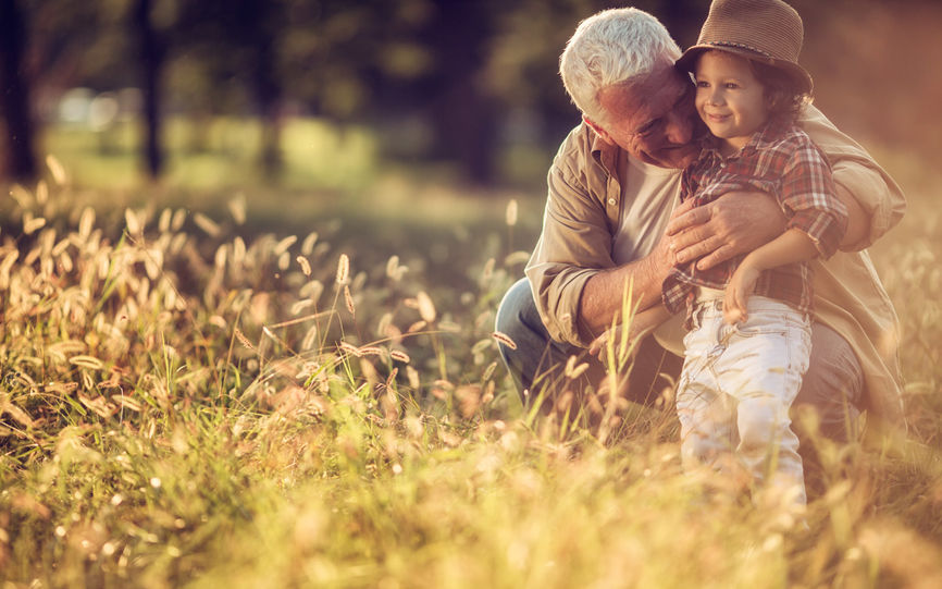 Bilde av en eldre mann holder rundt et barn i korneng.