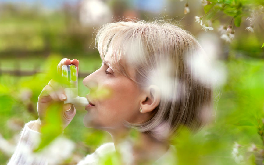 Bilde av en eldre dame som holder en inhalator opp til munnen.