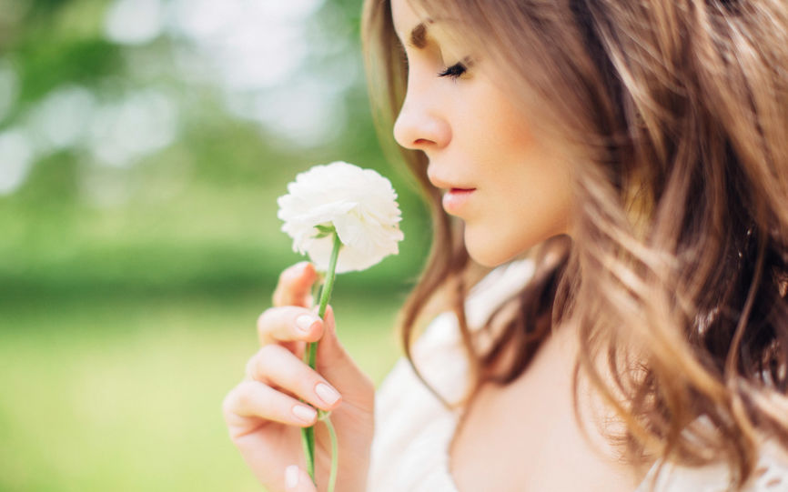 Ung kvinne lukker øynene mens hun lukter på en blomst