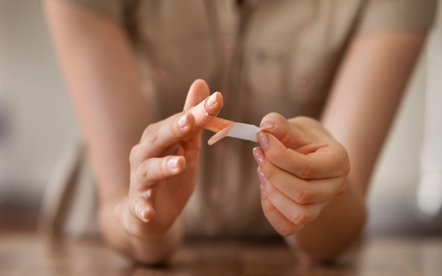 Bilde an en person som setter plaster på en finger.