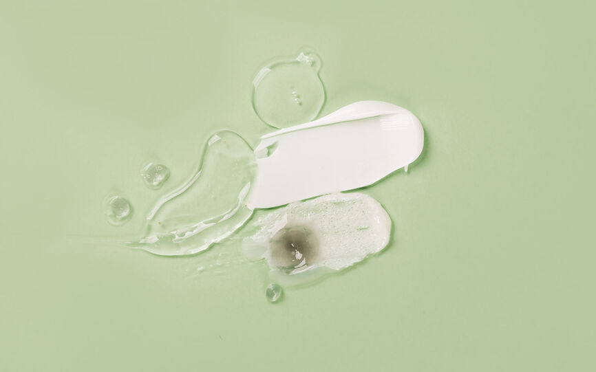 Bilde av hudpleieformuleringer som krem, gel og serum med ulike hudpleieingredienser smurt på ut på lys grønn bakgrunn.