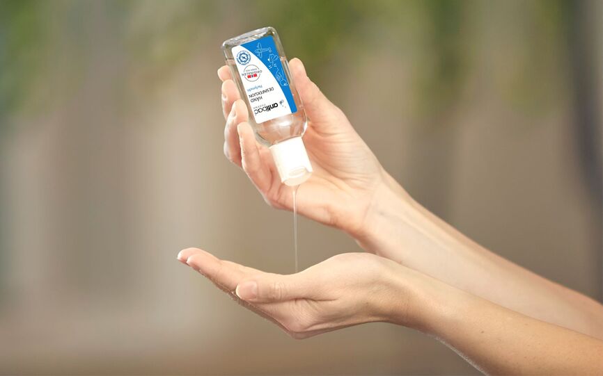 Nærbilde av hender som holder en liten flaske antibac opp ned. Innholdet dryppes ned i den ene hånden. Antibac kan brukes for å opprettholde håndhygiene på festivaler og arrangementer.