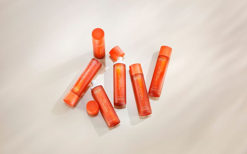 6 oransje flasker med IDUN Minerals Ready Set Fix Setting Spray presentert liggende på hvit bakrgrunn.
