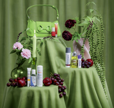 Bilde av en liten grønn veske på en pidestall med grønn duk. I forkant presenteres produkter som kan være nyttige på storbyferie.