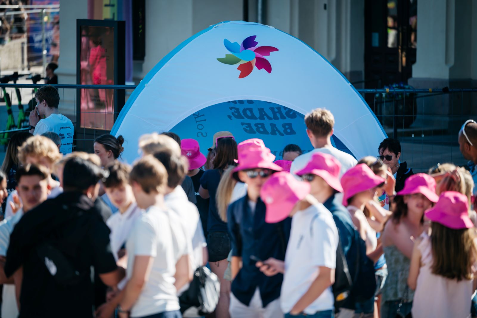 Bilde av en gruppe barn og ungdommer med rosa solhatter i forkant av et uv-telt med Kreftforeningens logo.